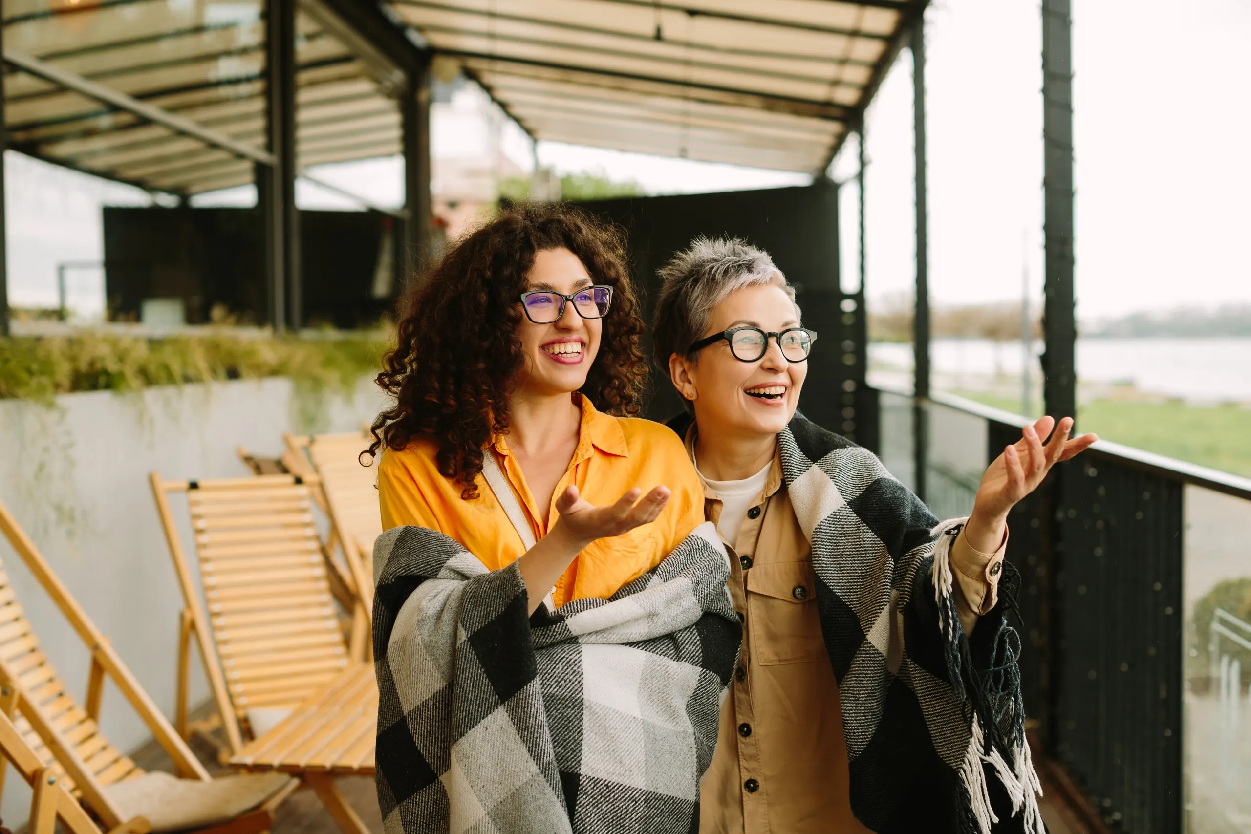 A mother and her adult daughter laughing together outdoors