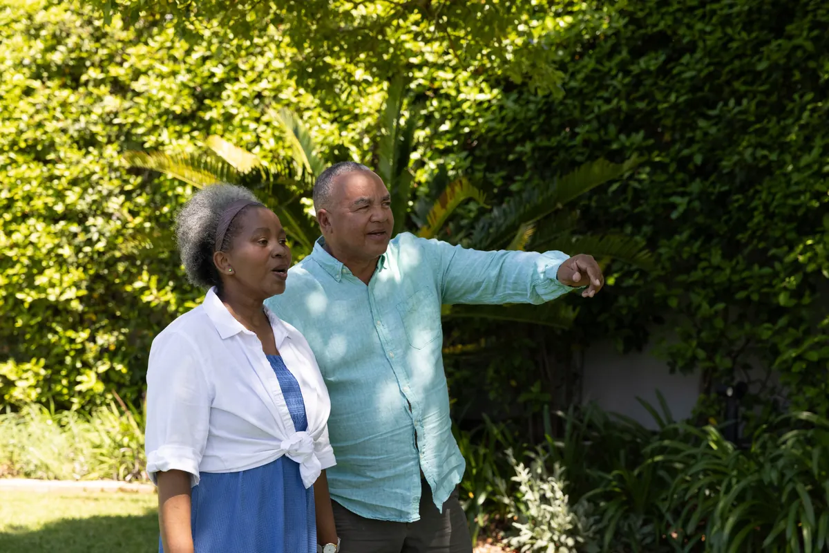 A senior couple walking together through a garden