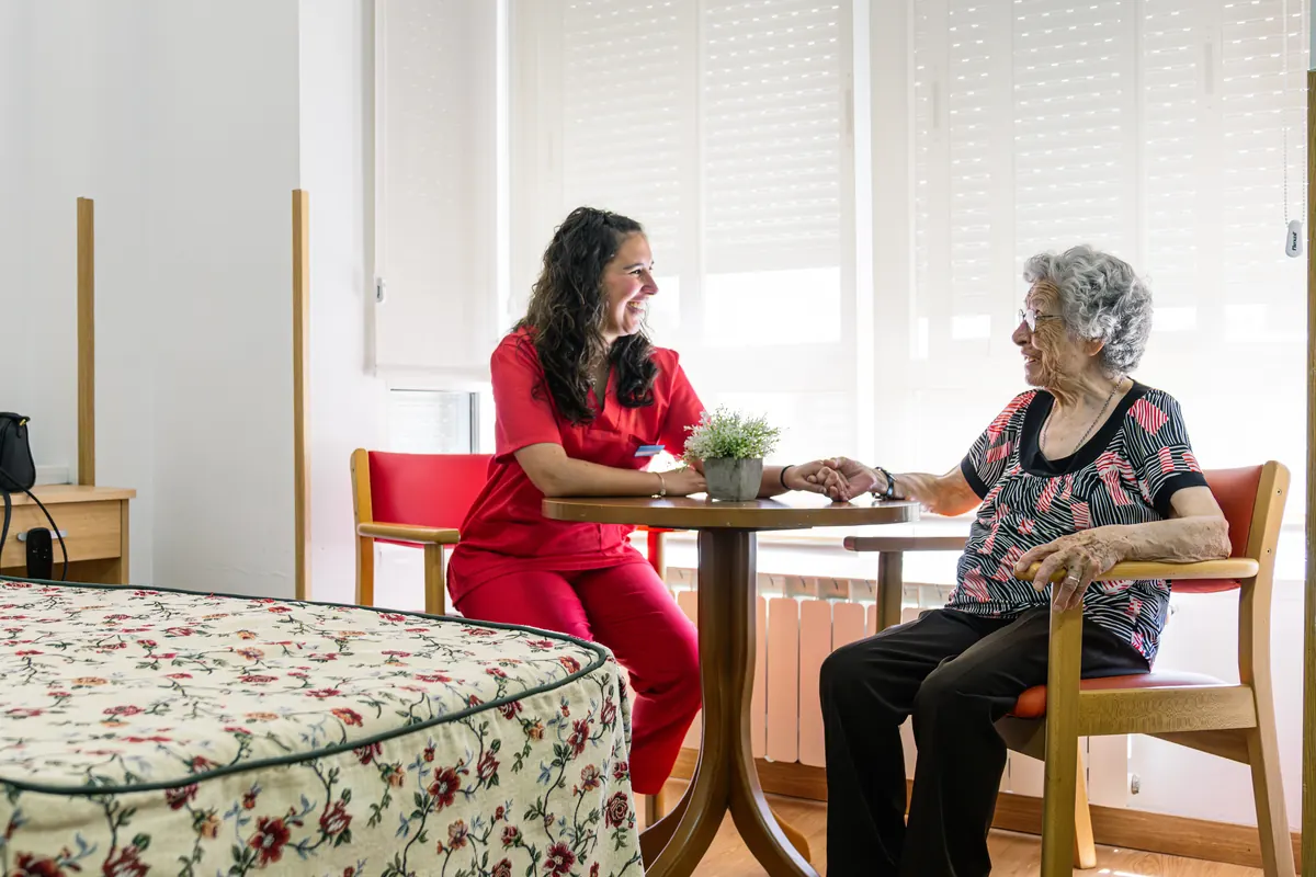 A nurse gently holding an elderly patient's hands